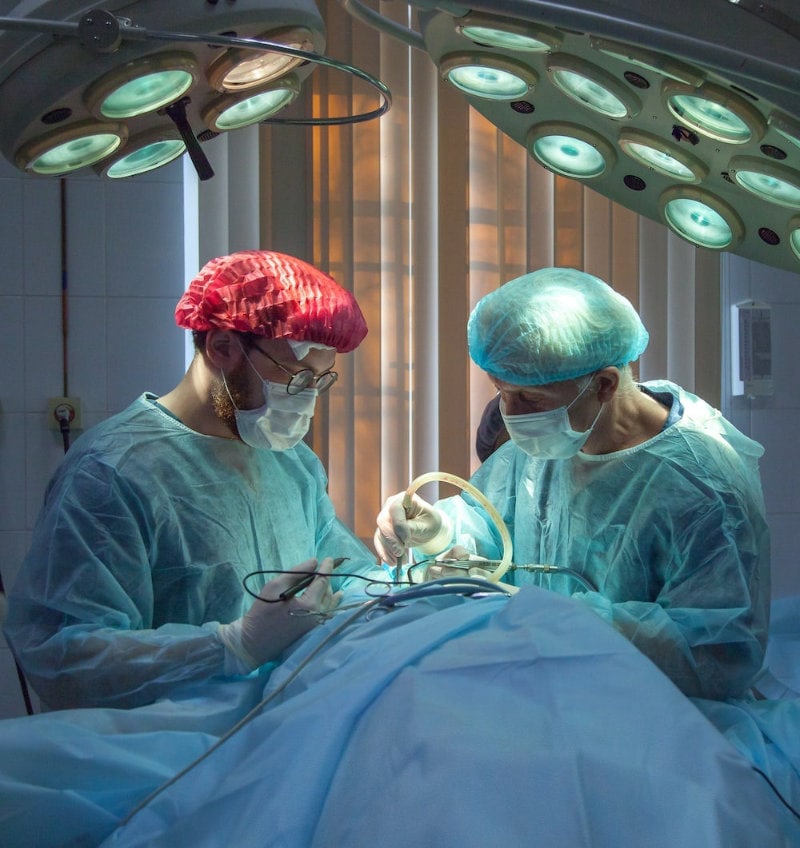 Two men performing surgery wearing blue smocks
